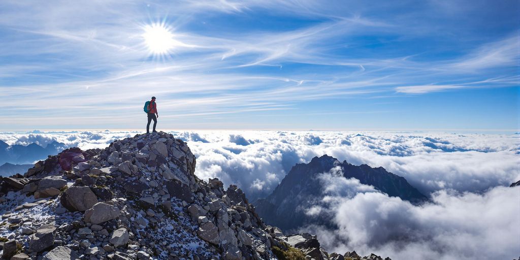 Person ascending a mountain peak at sunrise.